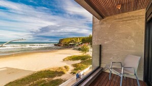 A balcony with a view of a beach and ocean, a chair, and a wooden ceiling. - Baluarte Pousada (Torres)