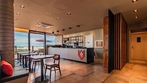 A modern hotel lobby with a bar area, seating, and a view of the beach. - Baluarte Pousada (Torres)