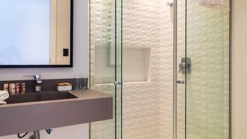 A modern bathroom with a glass-enclosed shower, a vanity with a mirror, and a toilet.