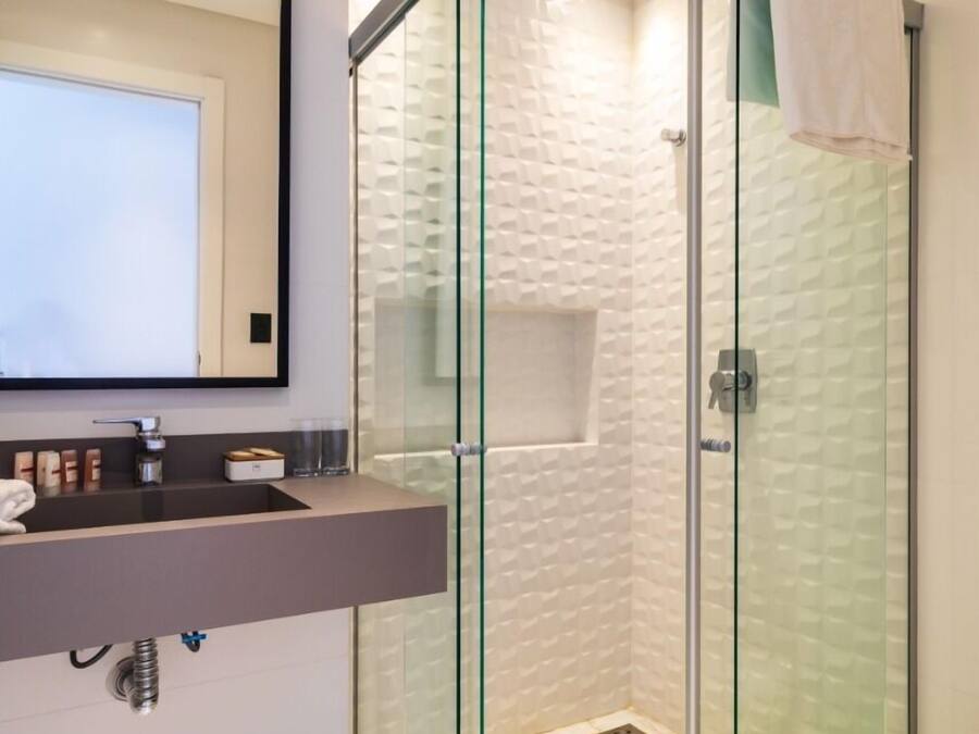 A modern bathroom with a glass-enclosed shower, a vanity with a mirror, and a toilet.