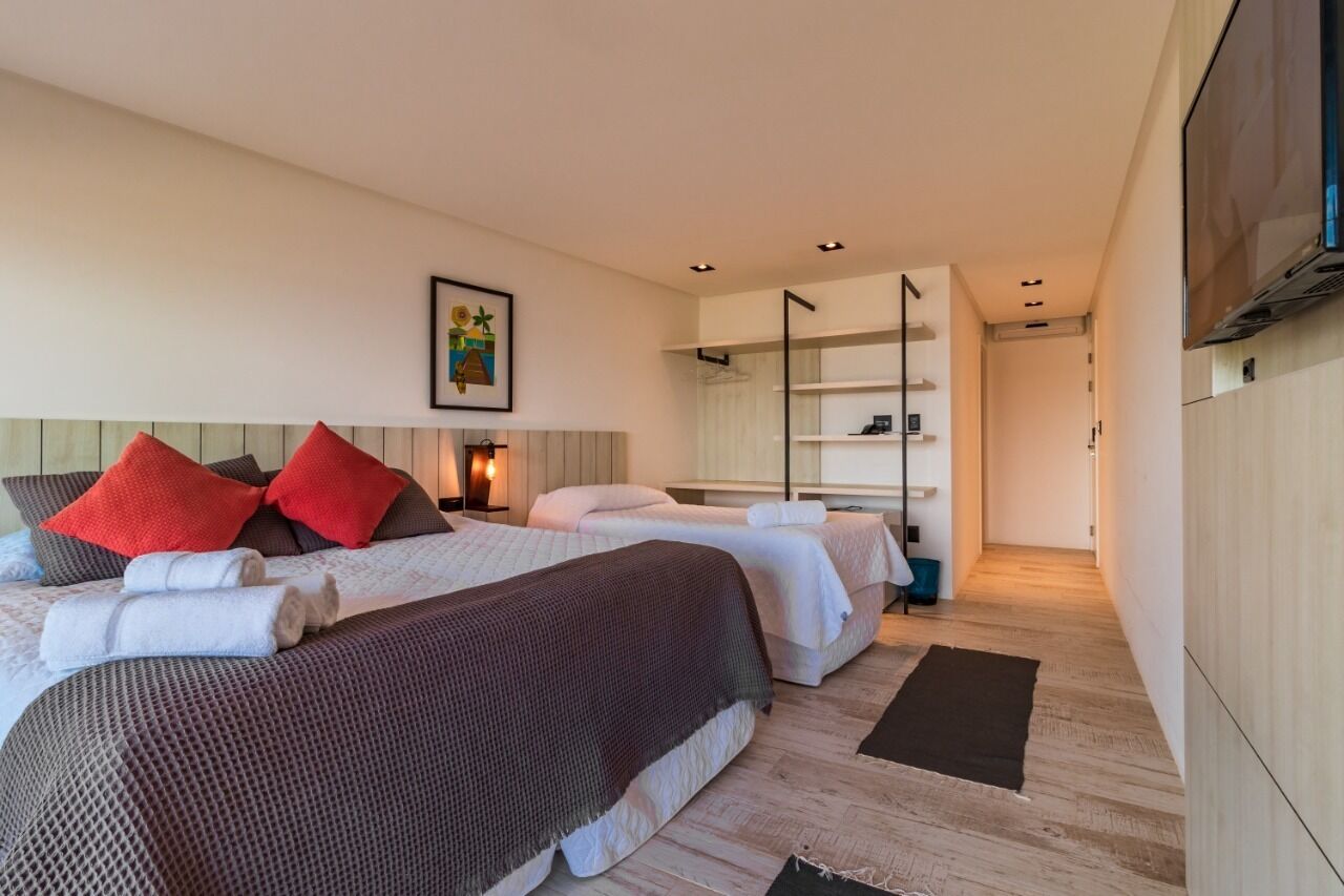 Et moderne hotelværelse med to senge, et fladskærms-tv, et natbord og et stort spejl.