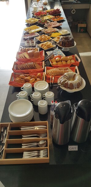A buffet table with various food items and dining utensils.