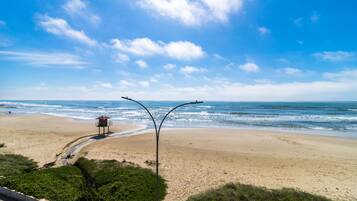 A beach with a lifeguard tower and a curved pathway leading to the water.