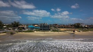 A beach with buildings in the background, a lifeguard tower, and a clear sky.