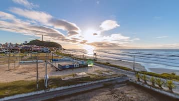 Zona costera con playa, una vía de tren y un pequeño edificio con un letrero.