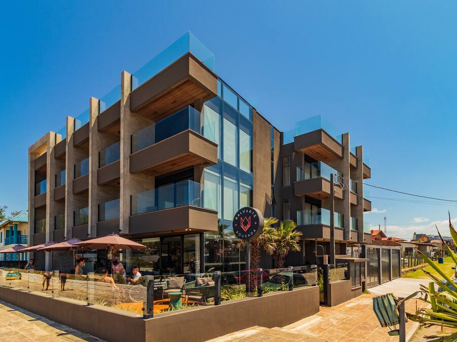 Un edificio moderno con varios balcones y una zona de restaurante con mesas al aire libre.