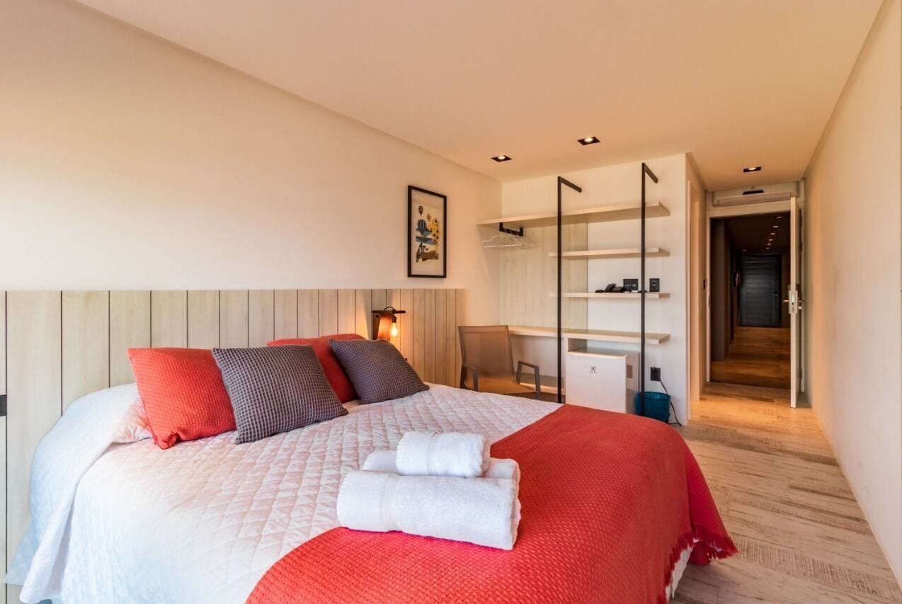 Una habitación de hotel moderna con una cama grande, un escritorio y un vestidor.