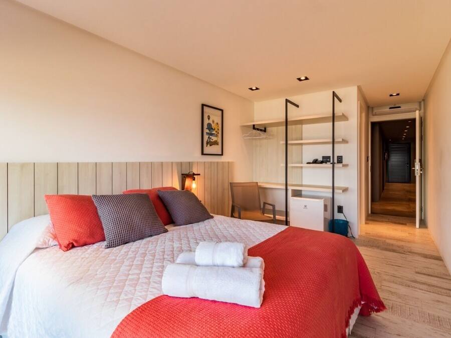 Una habitación de hotel moderna con una cama grande, un escritorio y un vestidor.