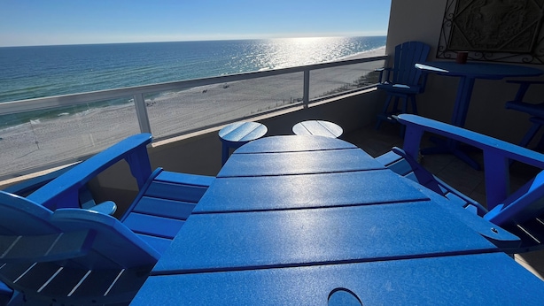 A balcony with blue furniture overlooking a beach. - Beautiful 7th floor condo ON THE BEACH (Orange Beach)