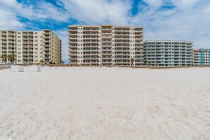 A beachfront hotel with multiple high-rise buildings, sandy beach, and clear sky.