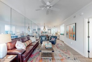 A spacious living room with a leather sofa, a coffee table, and a chandelier.