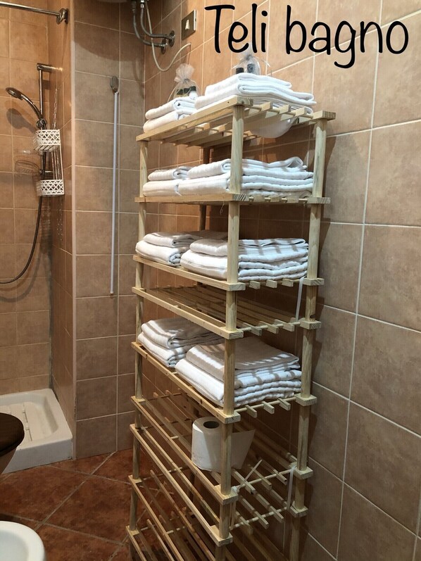 A bathroom with a wooden towel rack holding multiple folded towels. - The timeless cottage (Aprilia)