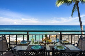 Un área de comedor al aire libre con vistas al océano, equipada con mesas y sillas.