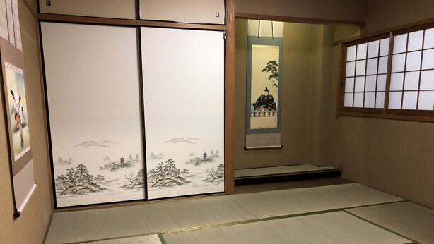 A traditional Japanese room with tatami flooring, sliding doors with artwork, and a shoji screen. - Osaka Namba House (Osaka)
