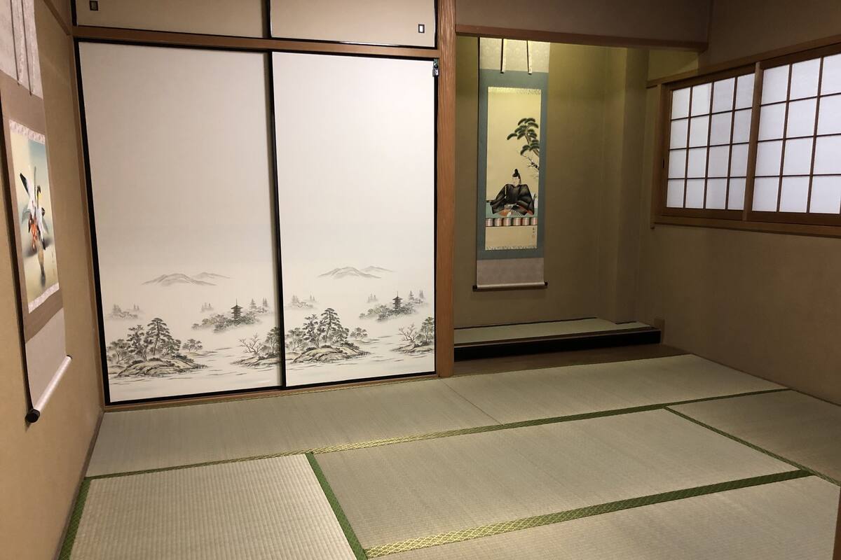 A traditional Japanese room with tatami flooring, sliding doors with artwork, and a shoji screen.