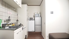 A compact kitchen with a sink, stove, microwave, and refrigerator.