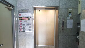 An elevator with a sign indicating floor levels and a security camera above it. - Osaka Namba House (Osaka)