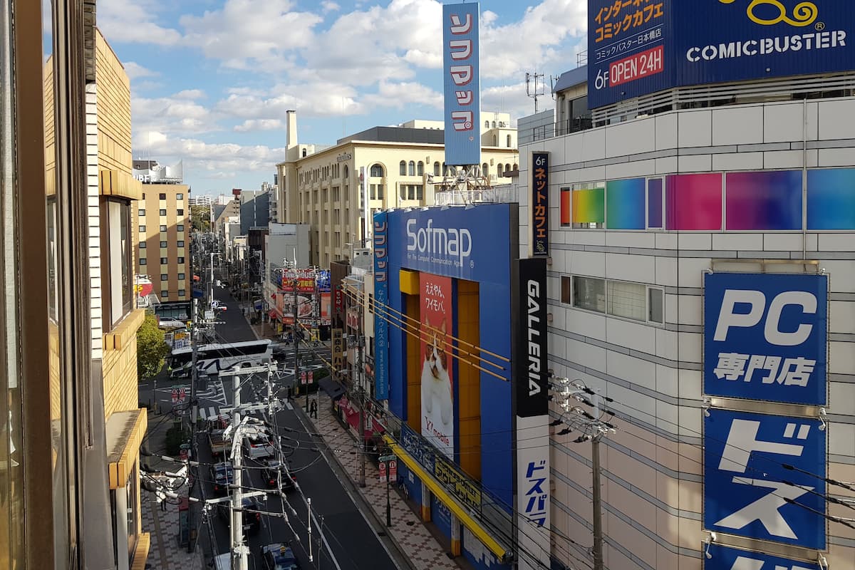 A busy urban street with commercial buildings, including a cafe and a gallery.
