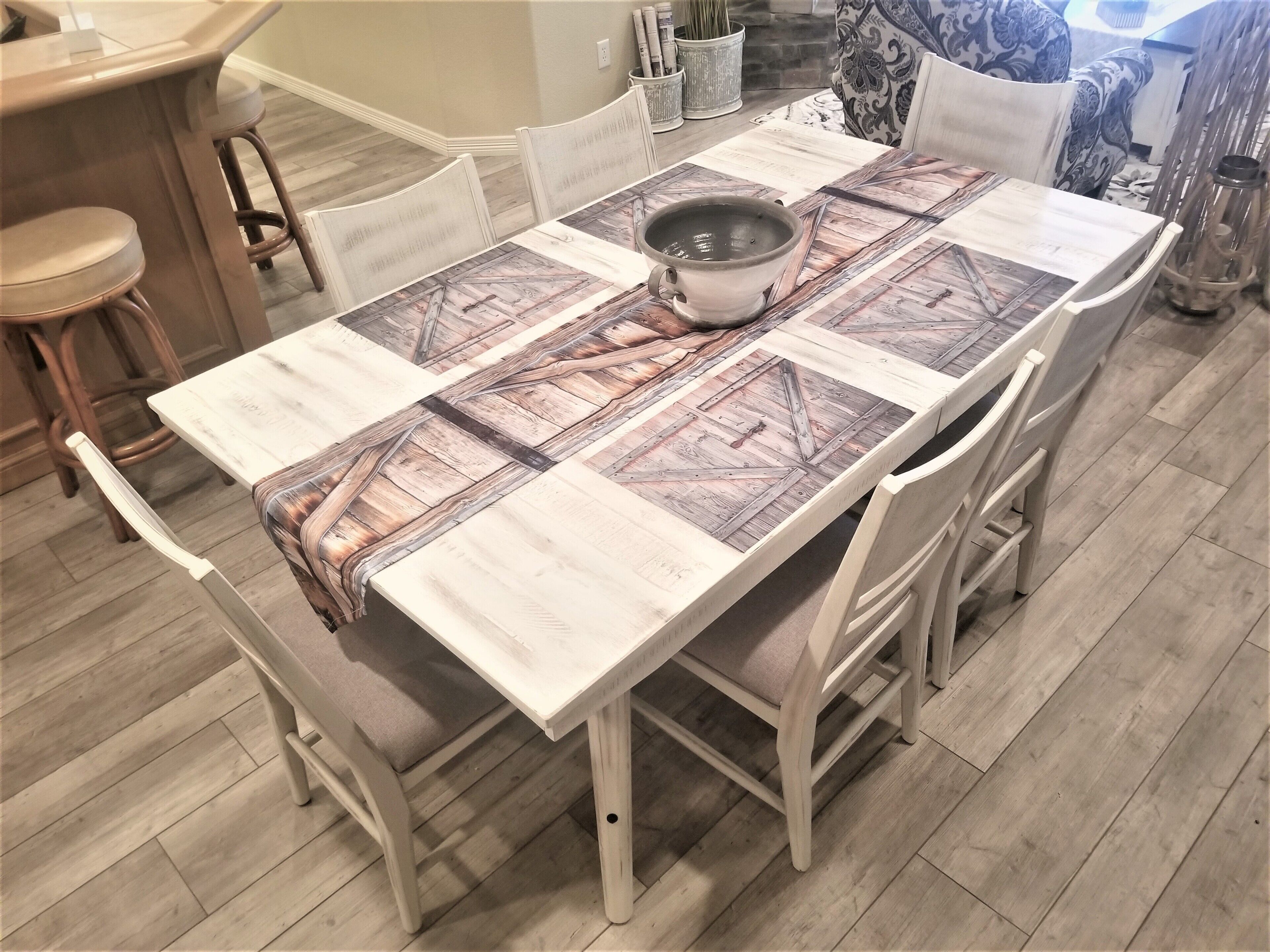 A dining table with a rustic design, surrounded by white chairs.