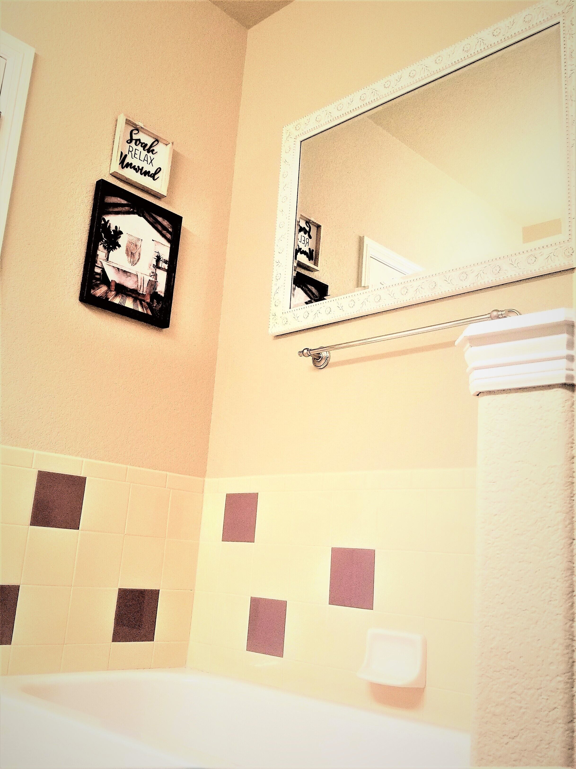A bathroom with a mirror, a towel rack, and a sign on the wall.
