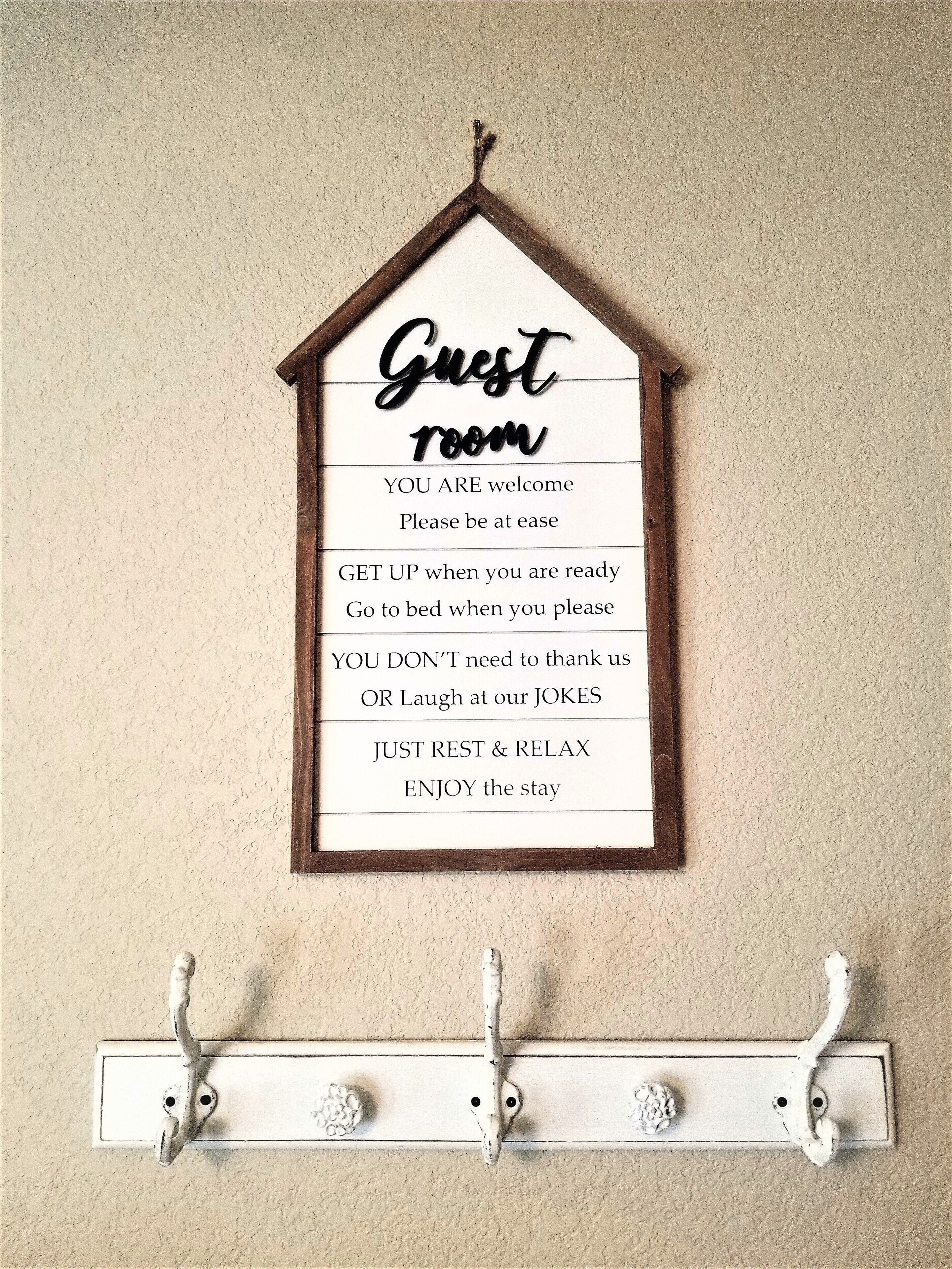 A wall-mounted sign with a house-shaped frame labeled "Guest Room" and instructions for guests.