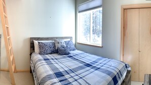 A bedroom with a bed, a wooden wardrobe, a ladder, and a window with a view of trees. - Schweitzer Ski Condo, Sandpoint, Lake Pend Oreille (Sandpoint)