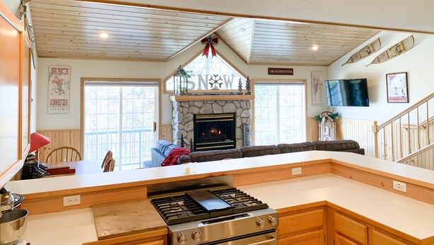 A spacious kitchen with a stone fireplace, wooden ceiling, and a large island. - Schweitzer Ski Condo, Sandpoint, Lake Pend Oreille (Sandpoint)