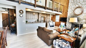 A spacious living area with a high ceiling, a kitchen with modern appliances, and a stone accent wall. - On Lake, WOW Views! 4 Kings, Big Deck. Walk to Marina, Concerts, Events (Dillon)