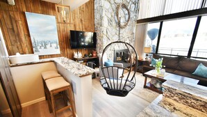 A modern living space with a kitchen area, a dining area with a high chair, a sofa, and a coffee table. - On Lake, WOW Views! 4 Kings, Big Deck. Walk to Marina, Concerts, Events (Dillon)