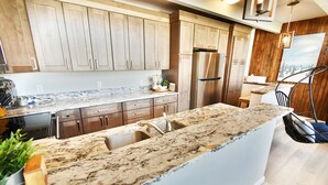 A modern kitchen with marble countertops, stainless steel appliances, wooden cabinets, and a view of the outdoors. - On Lake, WOW Views! 4 Kings, Big Deck. Walk to Marina, Concerts, Events (Dillon)