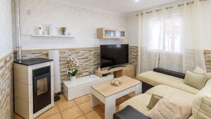Un espace de vie compact comprenant un coin cuisine, un téléviseur à écran plat, un canapé et une petite table.