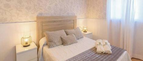 A bedroom with a bed, bedside lamps, and a nightstand.