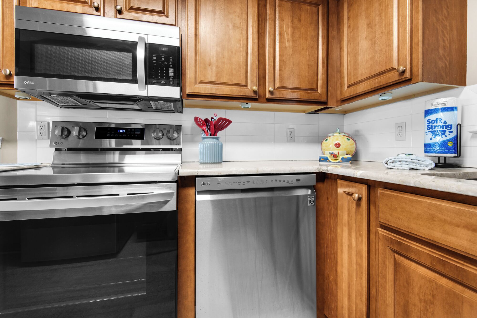 A kitchen with stainless steel appliances, wooden cabinets, a microwave, an oven, and a dishwasher.