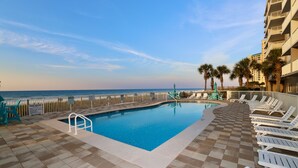 A pool area with a view of the ocean, surrounded by lounge chairs and palm trees. - Sandy Key 731: 3 BR/2 BA Perdido Key Beachfront Condo, On-Site Rental Office, Sleeps 8 (Pensacola)