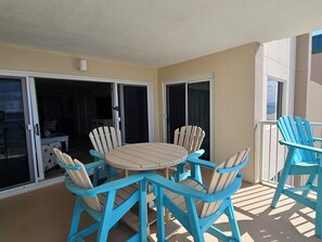 Een balkon met een ronde tafel en vier stoelen, een schuifpui en uitzicht op de stad.