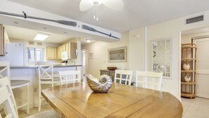 A dining area with a wooden table, white chairs, and a decorative shell centerpiece. - Sandy Key 731: 3 BR/2 BA Perdido Key Beachfront Condo, On-Site Rental Office, Sleeps 8 (Pensacola)