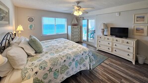 A bedroom with a bed, dresser, TV, and a view of the ocean through the window. - Sandy Key 731: 3 BR/2 BA Perdido Key Beachfront Condo, On-Site Rental Office, Sleeps 8 (Pensacola)