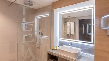 Een moderne badkamer met een glazen douchecabine, een grote spiegel en een inbouwwastafel.