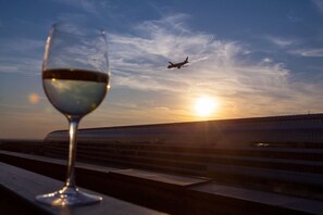 Un verre de vin, un coucher de soleil en toile de fond et un avion qui passe.