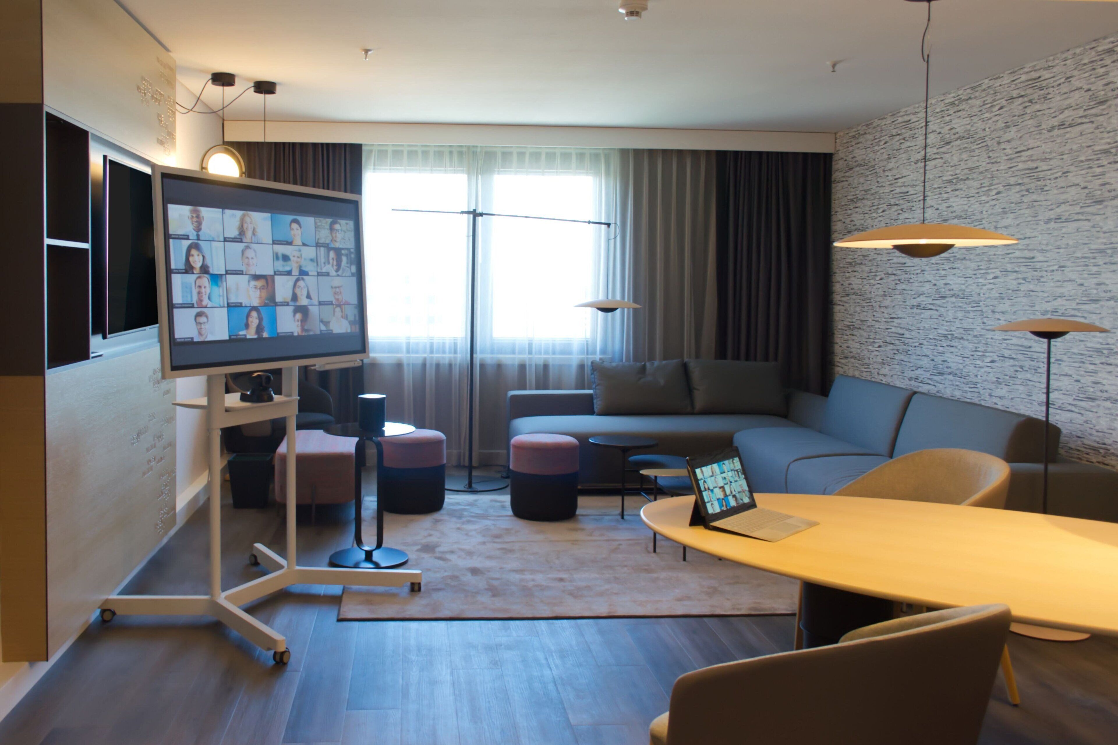 A modern living room with a flat-screen TV, a sofa, a coffee table, and a dining area with chairs.