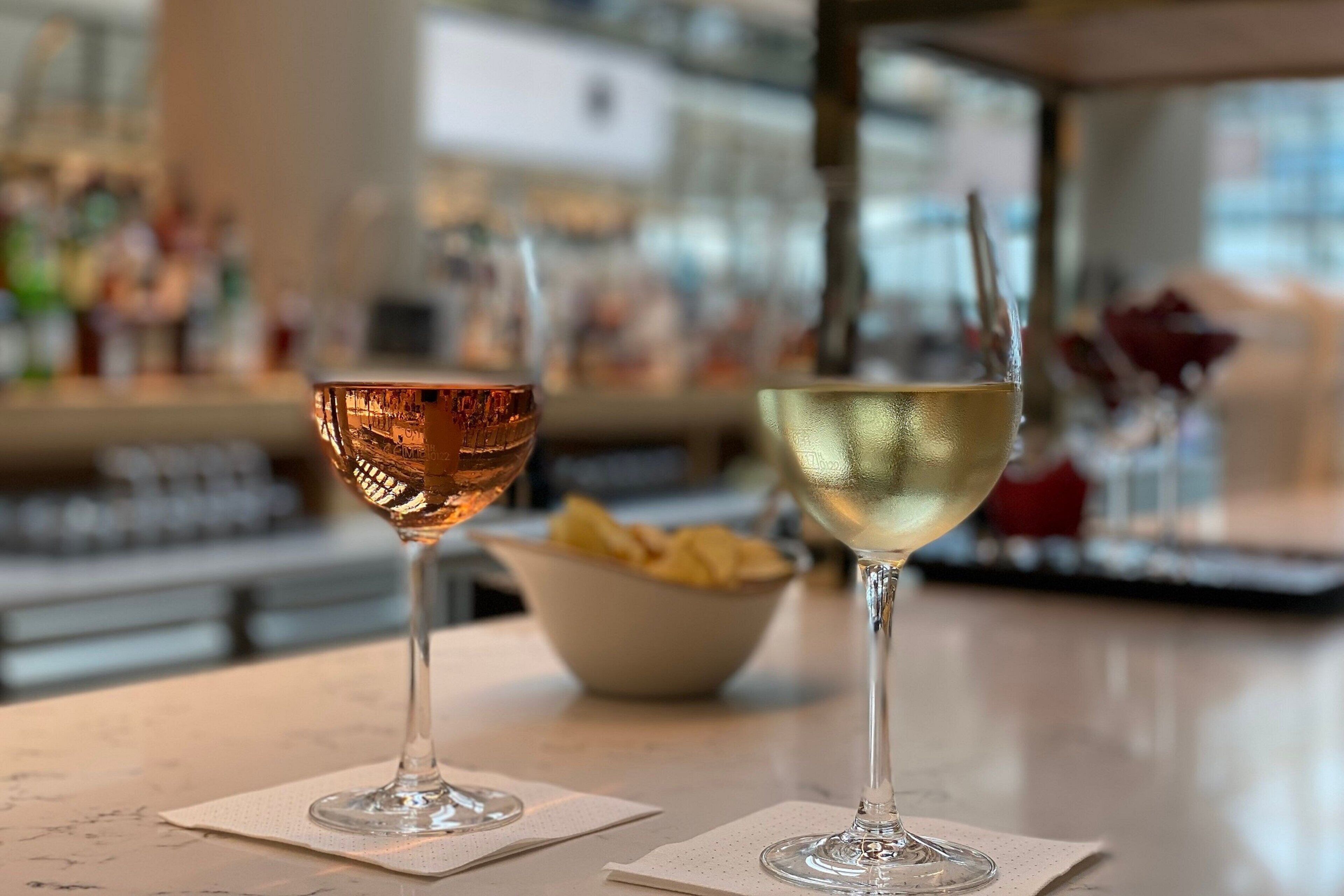 Two wine glasses on a table with a blurred background of a bar area.