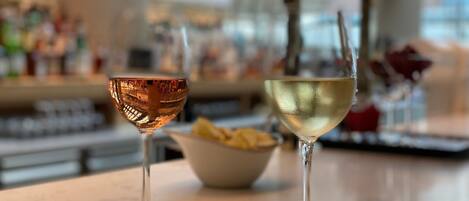 Two wine glasses on a table with a blurred background of a bar area.