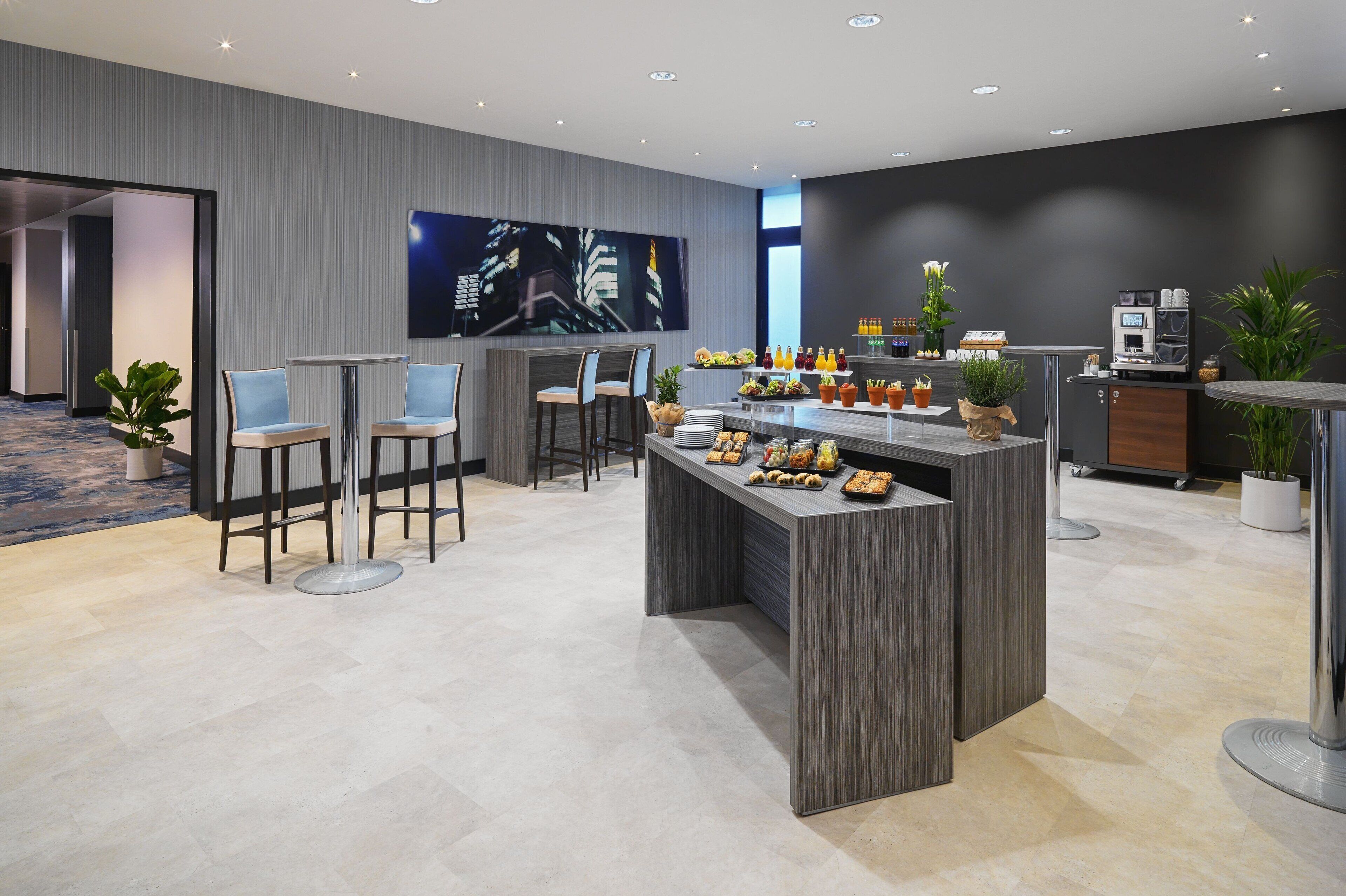 A modern hotel lobby with a bar area, seating, and a large cityscape painting.