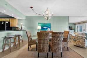 A dining area with wicker chairs, a glass table, and a chandelier.