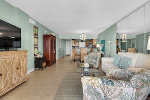 A spacious living room with a television, a large wooden cabinet, and a patterned sofa.