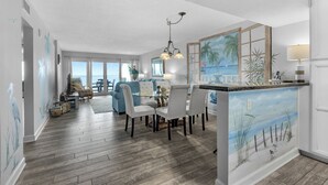 Amplia sala de estar con comedor, una isla de cocina con obras de arte y vistas al exterior.