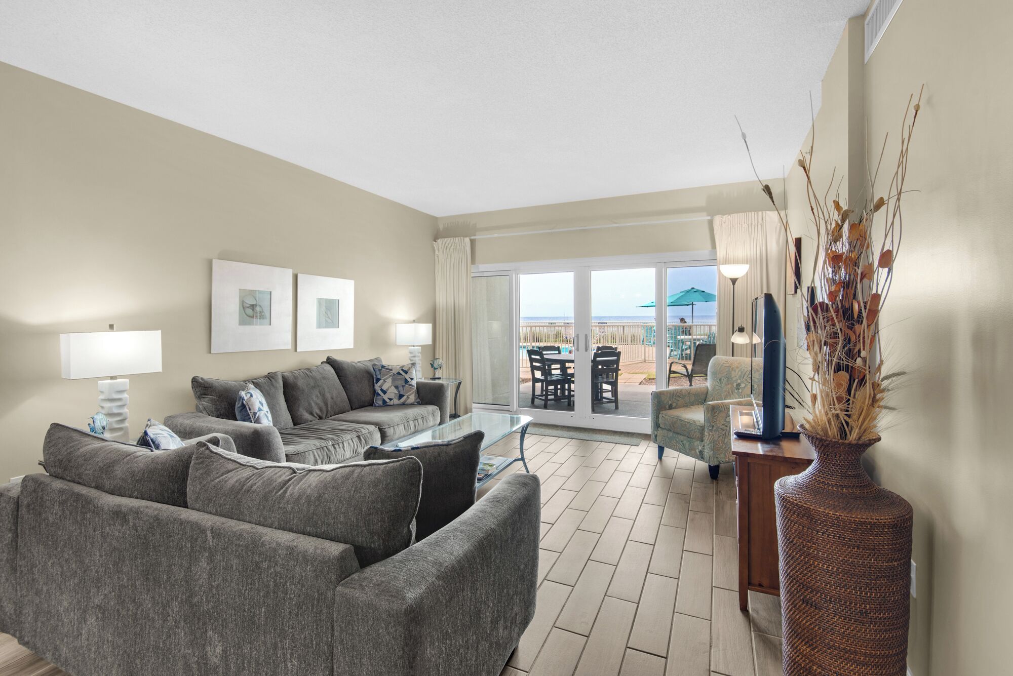 A modern living room with a sofa set, a glass coffee table, and a view of the outdoor patio area.