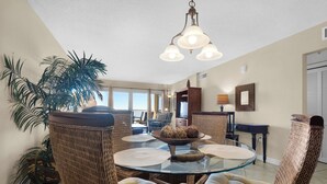 A dining area with wicker chairs, a glass table, and a chandelier. - Sandy Key 416:  2 BR / 2BA Gulf Front Condo in Perdido Key, FL.  Sleeps 6 (Perdido Key)