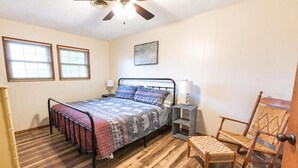 Une chambre à coucher avec un lit, des lampes de chevet, une chaise et un plancher en bois.