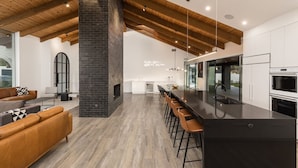 A modern kitchen with a central island, wooden beams, and a stone fireplace. - Luxury Camelback Mountain Views, Theater, Sauna, Heated Pool, Spa (Phoenix)
